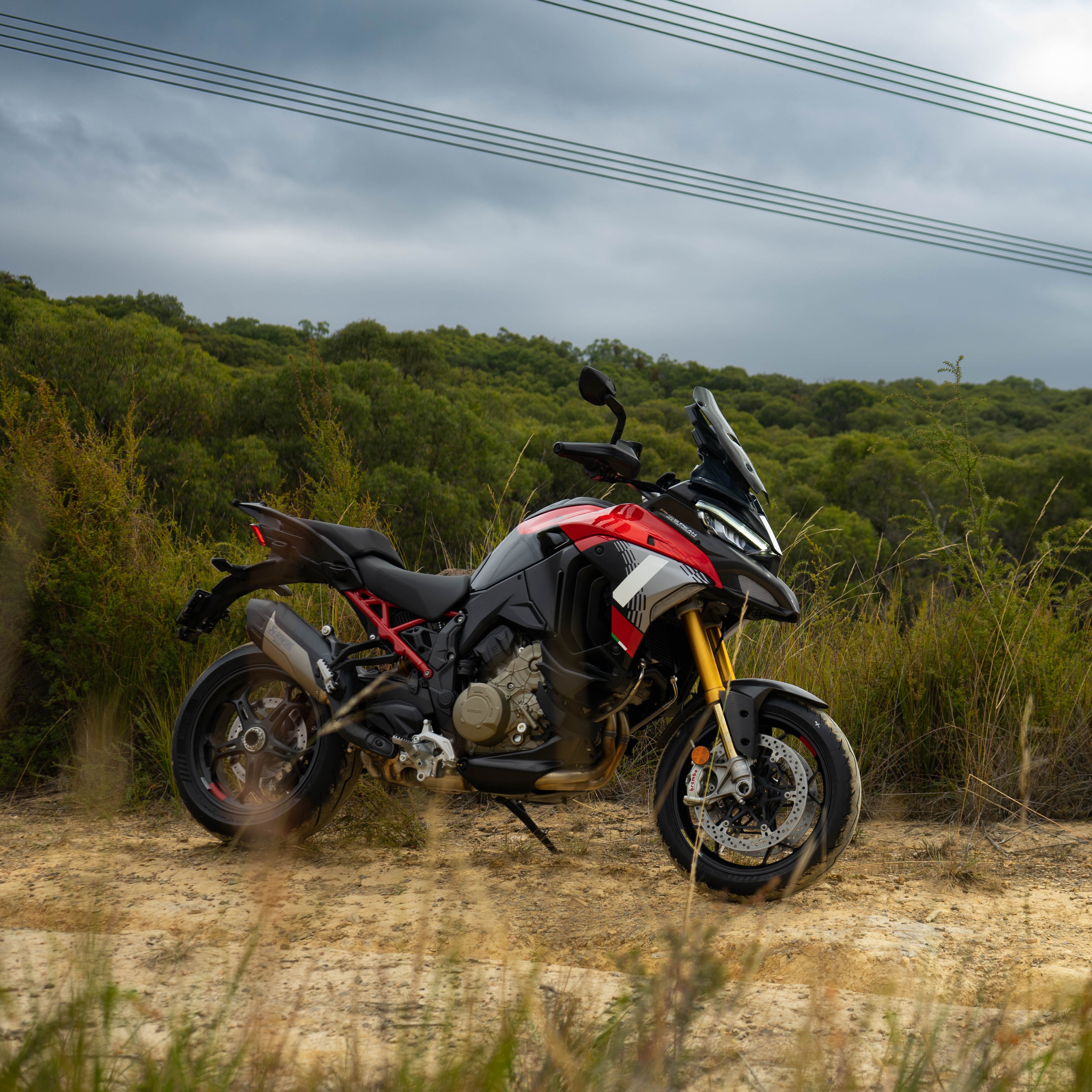 Motorcycle parked on a dirt road with a forest in the background