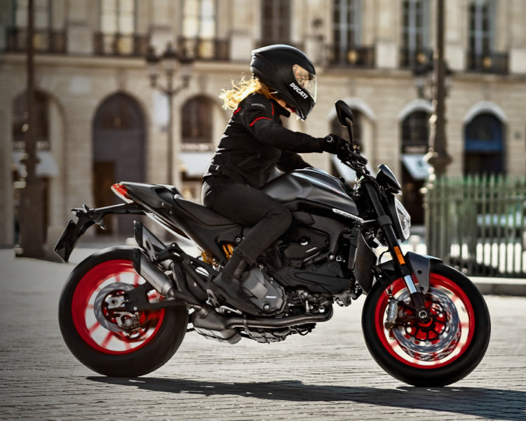 Person riding a Ducati Monster motorcycle in an urban setting