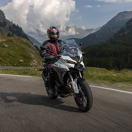 Motorcyclist on a scenic mountain road with a helmet and protective gear.